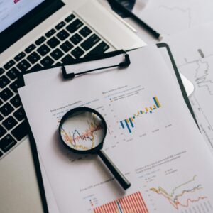 Overhead view of financial charts, laptop, and magnifying glass, ideal for business analysis themes.